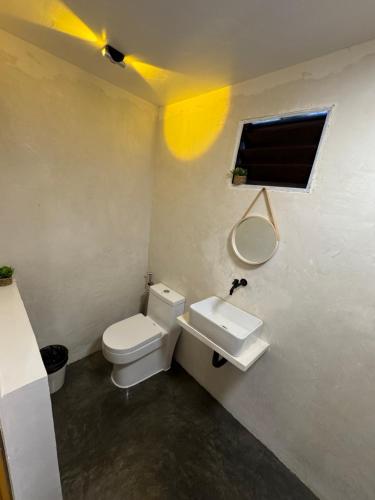 a bathroom with a toilet and a sink and a window at NUTMEG Cottage Siargao- Private room in General Luna