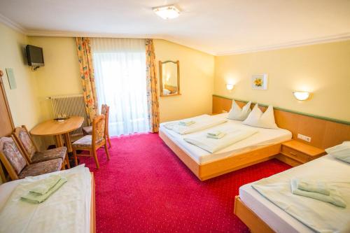 a hotel room with two beds and a table at Schnitzl-Eck in Flachau