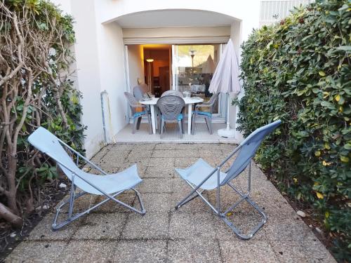 deux chaises et une table sur une terrasse dans l'établissement Studio cabine avec accès direct piscine collective et plage - 4FR503, à Saint-Cyprien