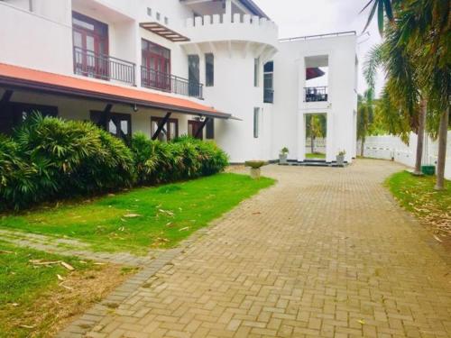 a large white building with a walkway in front of it at Kamatha Hotel & Restaurant in Ambalantota