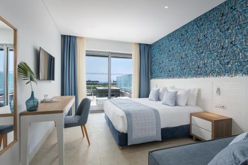 a hotel room with a bed and a desk and a window at Blue Lagoon Queen in Kalyves Poligirou