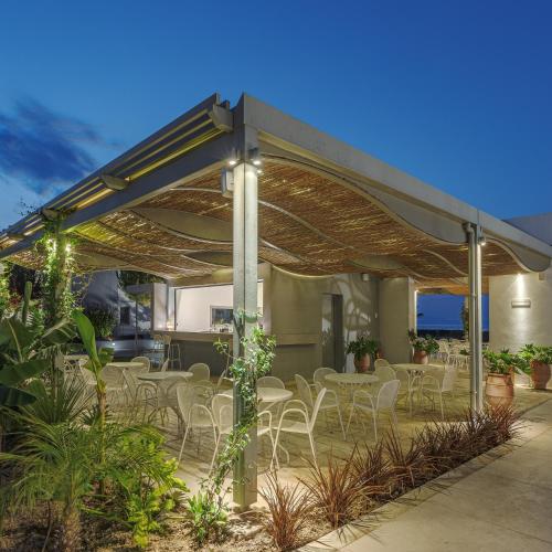 a patio with tables and chairs under a pergola at Blue Lagoon Queen in Kalyves Poligirou