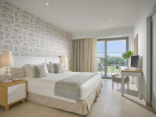 a bedroom with a bed and a desk and a television at Blue Lagoon Queen in Kalyves Poligirou