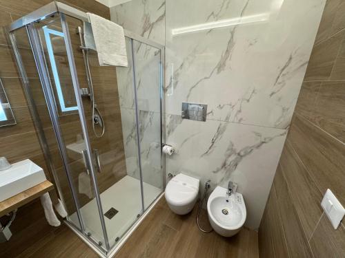 a bathroom with a shower and a toilet and a sink at Hotel Cocceio in Bacoli