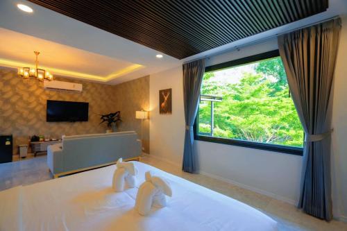 a bedroom with two white towels on a bed with a window at Natthapon Resort Kaeng Kachan in Kaeng Krachan