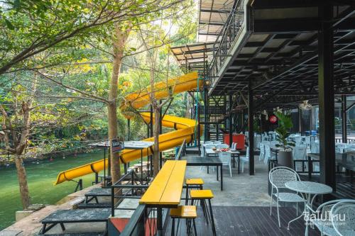 a cafeteria with yellow benches and tables and tables at Natthapon Resort Kaeng Kachan in Kaeng Krachan