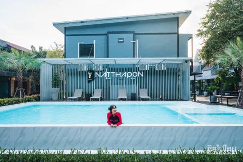 a little girl sitting on the edge of a swimming pool at Natthapon Resort Kaeng Kachan in Kaeng Krachan
