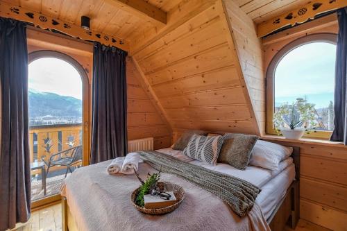 a bedroom in a log cabin with a bed and two windows at Odkryj-Zakopane Tatra View Houses & SPA in Kościelisko
