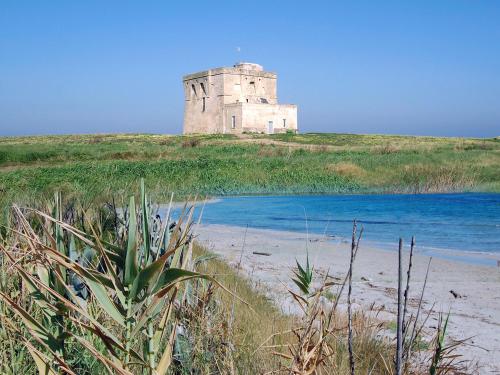 an old tower on top of a hill near the water at Al Ristoro in Torre Santa Sabina