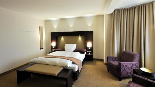 a hotel room with a bed and a chair at Wellings Parkhotel in Kamp-Lintfort