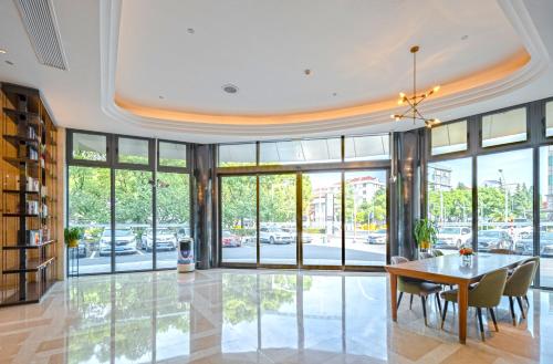 a dining room with a table and chairs and windows at Yunfei Hotel - Shanghai Hongqiao Wuzhong Road Branch in Shanghai