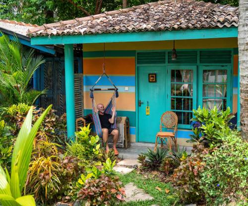 a woman sitting on a hammock outside a blue house at Villa My Way Yoga Holiday in Ahangama
