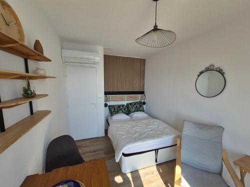 une petite chambre avec un lit et un miroir dans l'établissement Studio 19m2 classé 1, vue sur étang de Thau, 200m des cures, 2eme Étage sans ascenseur, à Balaruc-les-Bains