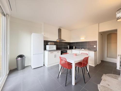 une cuisine avec une table blanche et des chaises rouges dans l'établissement Havre de Lens - Centre-ville - 100m de la gare, à Lens
