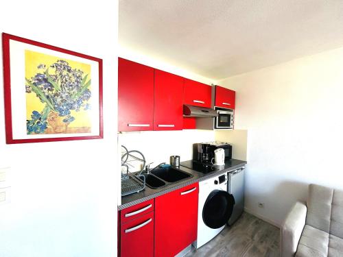 une petite cuisine avec des armoires rouges et un évier dans l'établissement Appartement 2 pièces 3 personnes - à 200 m de la plage, à Ploemeur