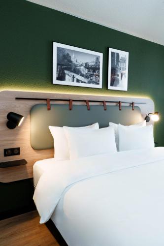a bedroom with two beds and a green wall at Campanile PRIME - Paris Ouest Boulogne in Boulogne-Billancourt