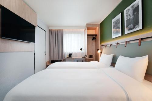 a hotel room with two beds and a flat screen tv at Campanile PRIME - Paris Ouest Boulogne in Boulogne-Billancourt
