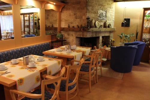 a restaurant with tables and chairs and a fireplace at Sevda's Hotel Garni Weinforth in Willingen