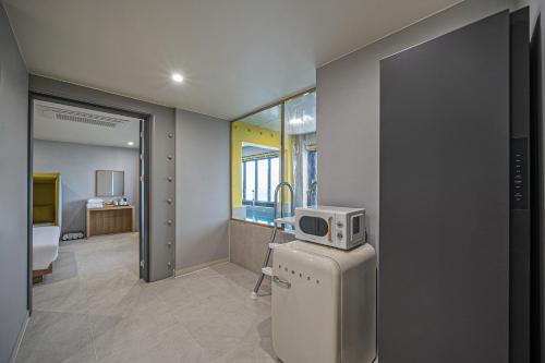 a room with a microwave on top of a refrigerator at From H Brown Dot Hotel Gyeongju Yangnam in Gyeongju