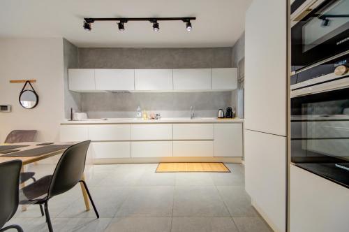 a kitchen with white cabinets and a dining table at Modern Marsaxlokk Apartment in Marsaxlokk