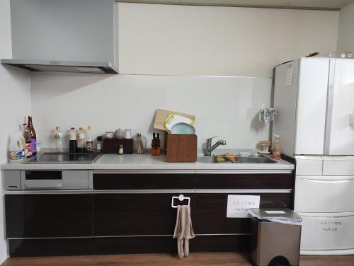 a kitchen with a sink and a refrigerator at Backpackers Kur Guesthouse Asahirou 旅人湯治客舎朝日楼 in Kaga