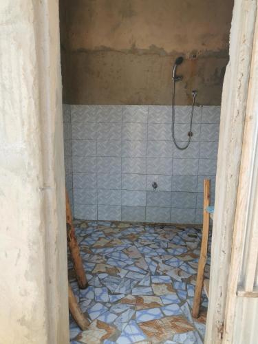 a bathroom with a shower and a tiled floor at Les jardins fleuris de lompoul sur mer in Tioukougne Peul
