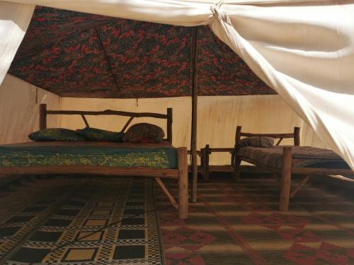 a room with two beds and an umbrella at Les jardins fleuris de lompoul sur mer in Tioukougne Peul