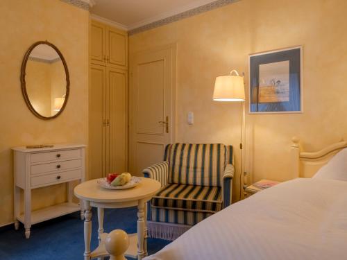 a hotel room with a bed and a chair and a table at Hotel Wiesbaden in Wenningstedt