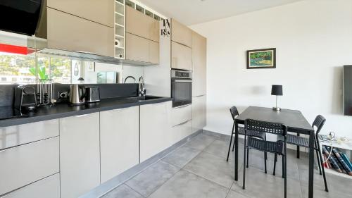 une cuisine avec des armoires blanches et une table et des chaises dans l'établissement Serenity Cannes Cozy One-Bedroom, à Cannes