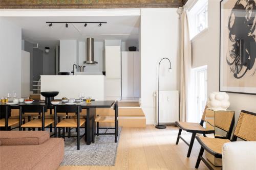 a kitchen and dining room with a black table and chairs at Unique 3 Bedroom Apartment in Vibrant Frederiksberg in Copenhagen