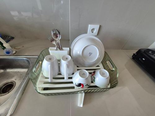 a tray with three cups and a plate on a sink at Apartemen Puri Orchard Lani's Transit Tower CH in Jakarta