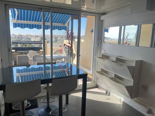 une salle à manger avec une table et des chaises et un balcon dans l'établissement CapNat - Village Naturiste - Port Nature - Le Bisou, au Cap d'Agde