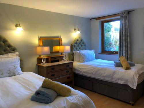 a bedroom with two beds and a window at Garden Bank Cottage in Kelso