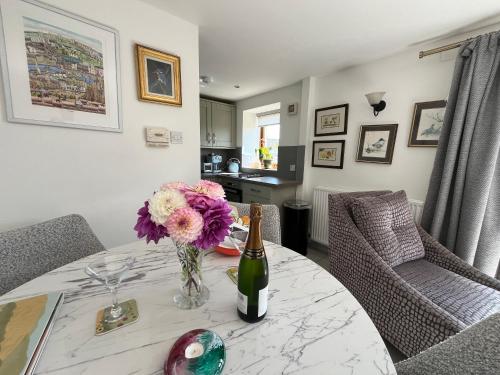 a table with a bottle of wine and flowers on it at Garden Bank Cottage in Kelso