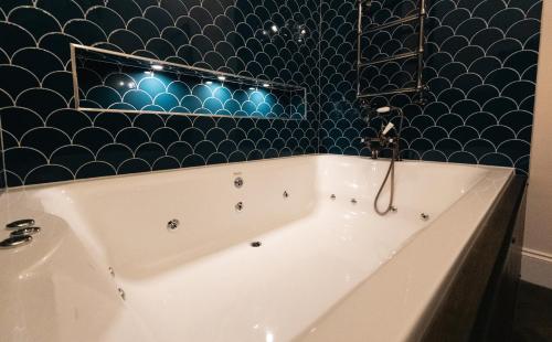 a bath tub in a bathroom with a blue tiled wall at St Hildas Complex in Hinderwell