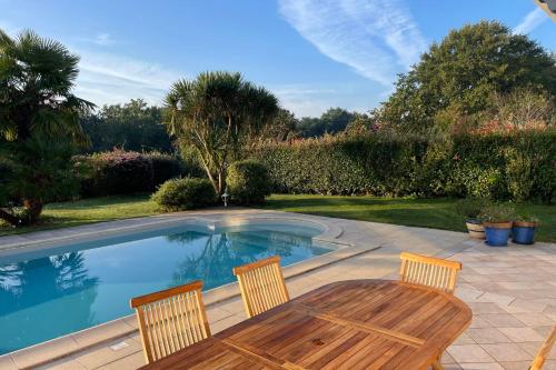 eine Terrasse mit Tisch und Stühlen neben einem Swimmingpool in der Unterkunft Villa on the Makila golf course near Biarritz in Bassussarry