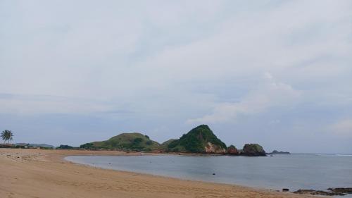 a beach with two islands in the water at Roby Homestay in Kuta Lombok
