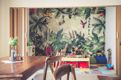 a dining room with a wall mural of tropical plants at Hotel Cabernet in Villánykövesd