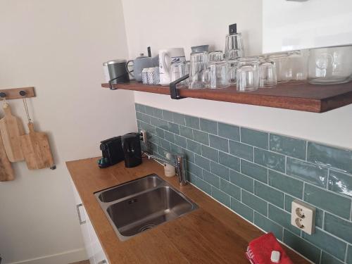 een keuken met een gootsteen en een plank met glazen bij Have a nice stay! - Apartment Duinvos 150m from the beach in Noordwijk aan Zee