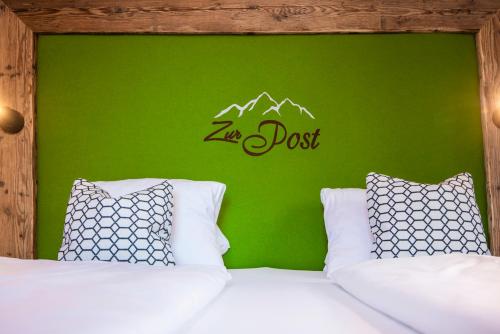 a bedroom with a green wall and a bed with two pillows at AlpinSpa zur Post - Bergbahn im Sommer 2025 inklusive in Bad Gastein