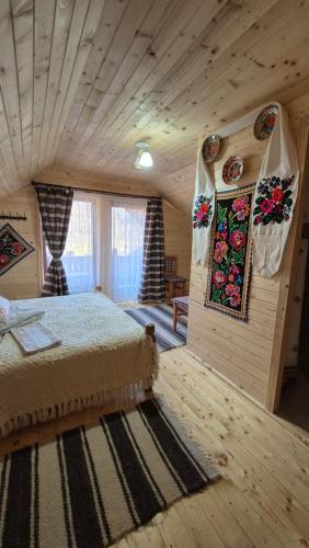 a bedroom with a bed in a log cabin at Casa Pintea de Sub Coastă in Breb