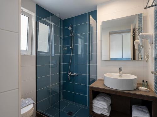 a blue tiled bathroom with a sink and a shower at Alexia Beach Hotel in Agia Marina Nea Kydonias