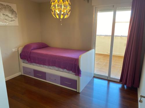 a bedroom with a bed with purple sheets and a chandelier at TERRASOL AZUCARERA ATICO LUJO in Torre del Mar