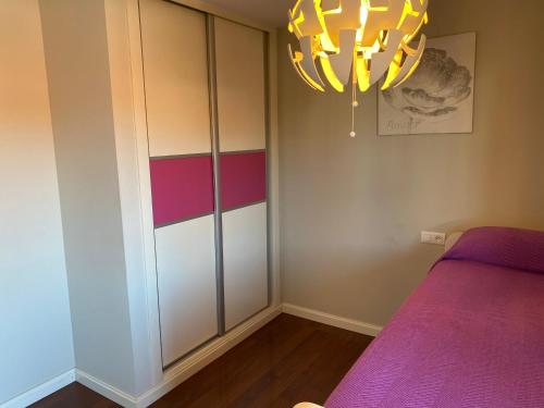 a bedroom with a purple bed and a chandelier at TERRASOL AZUCARERA ATICO LUJO in Torre del Mar