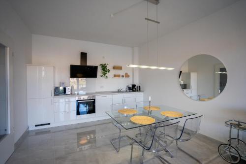 a kitchen with a glass table with chairs and a mirror at Tomkes Ferienwohnung am See in Rhauderfehn