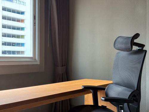 a chair sitting in front of a desk with a window at Centric Place Hotel in Bangkok