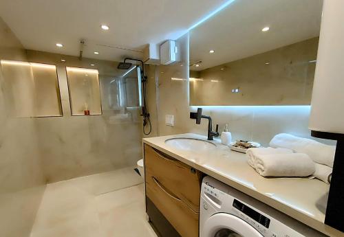 a bathroom with a sink and a washing machine at Tirana Sunset Retreat Stylish Loft by the Lake Park in Sauk