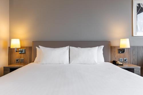 a large bed with white pillows in a hotel room at Holiday Inn London West by IHG in London