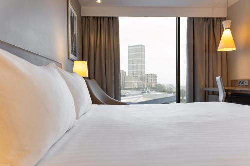 a hotel room with a bed with white pillows and a window at Holiday Inn London West by IHG in London
