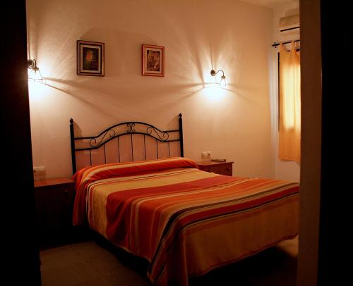 a bedroom with a bed and two pictures on the wall at El Aceitón in Cortegana